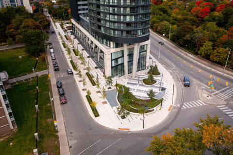 An aerial photograph of a building and surrounding sidewalk, with plant and trees